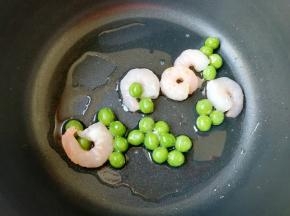 下入腌制好的虾仁和青豆划炒至熟。