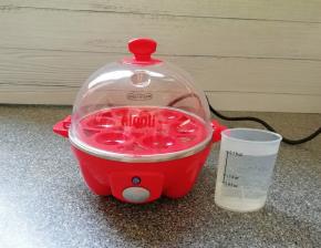 准备好煮蛋器，用量杯取适量的水加入到蒸盘里面。