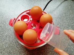 用量杯下面的钢针将鸡蛋大头一端戳一个小洞(避免煮的过程中鸡蛋破裂)，将鸡蛋放在蛋托盘上面。