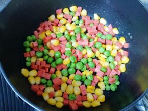 不粘锅内刷一层食用油，下入豌豆、玉米粒和火腿肠翻炒均匀，放盐和鸡精调味，盛出备用。