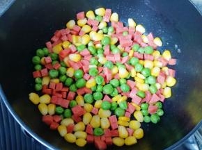 不粘锅内刷一层食用油，下入豌豆、玉米粒和火腿肠翻炒均匀，放盐和鸡精调味，盛出备用。