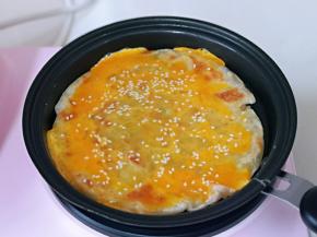 用刮刀将鸡蛋铲均匀，撒上熟白芝麻，把手抓饼翻面。