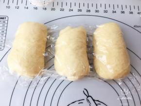 取出面团，分成三等份，擀成长椭圆型排气，再卷起，加盖保鲜膜醒发十五分钟。