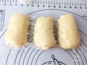 取出面团，分成三等份，擀成长椭圆型排气，再卷起，加盖保鲜膜醒发十五分钟。