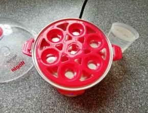 准备好煮蛋器，放上蛋托盘，用量杯取最高水位的水加入到蒸盘里面。