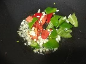 锅里放入蒜、姜、青红椒煸香