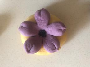 贝果胚表面刷水 把做好的紫薯面片摆上 轻压贴合，中心用刮刀把压一下