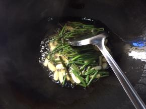 锅中倒入适量食用油，下葱段和蒜瓣，小火煎