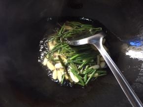 锅中倒入适量食用油，下葱段和蒜瓣，小火煎