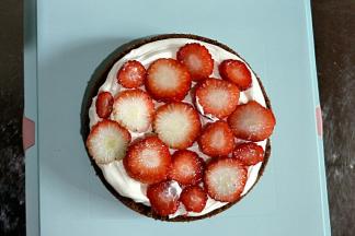 在第一层蛋糕胚上涂一层奶油后放入草莓片