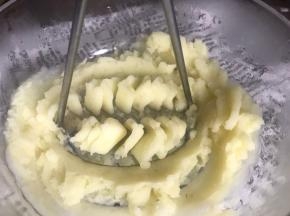 取出蒸好的土豆，倒入大点的容器中，压成泥状