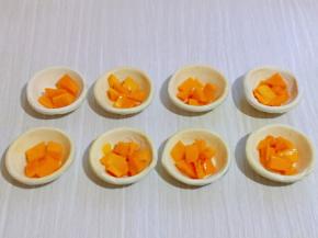 将切好的芒果果肉放入蛋挞皮中，如图。