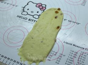 松弛好的面团压扁，用擀面杖擀成长方形面片。