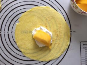 先舀上一层奶油，再放上一块芒果