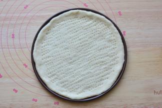 放在披萨盘里面，用叉子在面饼上面扎一些小孔，防止烤的时候鼓起来