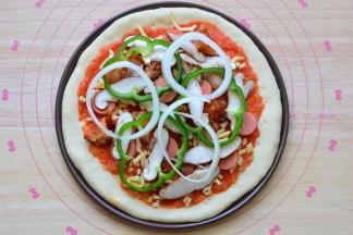 撒上一层芝士，摆上鸡腿肉、火腿肠、香菇、洋葱和青椒