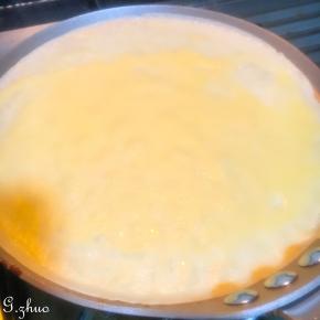 小火热锅后倒入一勺面糊左右摇摆煎锅摊至均匀，面糊约80克，小火煎至表面鼓出小泡即可离火，直接向盘内倒扣煎锅，轻微晃动即可自动脱落。