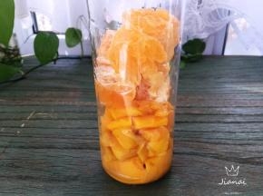 将芒果果肉与澳柑果肉一同放进果汁杯中。