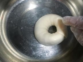 发酵好的贝果可提前放入冰冷冻半小时，另一种方法是用碱水加温水，先放温水再放烘焙碱，是烘焙碱哦，不是家里的食用碱，那口感并不好，操作时请带上一次性手套，双面在碱水中稍微翻滚后沥干水，放入烤盘，