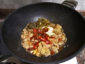 放入酸菜、大蒜、泡椒和泡姜翻炒片刻。