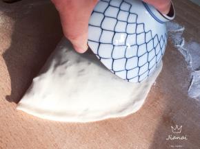 再将空白的一半饼皮折过来，盖住馅料，并用手指轻轻按压边缘留白处，使其粘合，用一只小碗，沿盒子边转半个圆，去掉多余的饼皮。