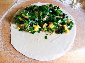 取一个剂子擀成约一毫米厚的饼皮，将馅料放在一半的位置，边缘处留白。