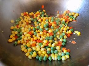 油锅烧热，放入玉米粒豌豆粒胡萝卜丁翻炒片刻