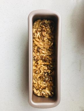 8、将黄油糊挤入学厨21厘米磅蛋糕模具中，抹平，在表面摆满核桃