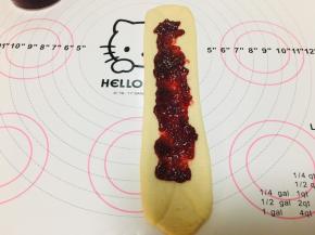 6、将左右两侧掀起向中间对折，轻轻按压至平整，擀长后将草莓酱涂抹在中间位置，四周边缘不涂抹