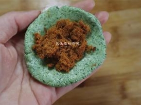 将面团分成40克一个的小剂子，手捏开，放入适量的蛋黄和肉松
