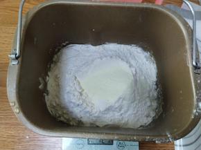让把纯净水放入面包桶内，加入酵母，然后加入面粉跟奶粉。