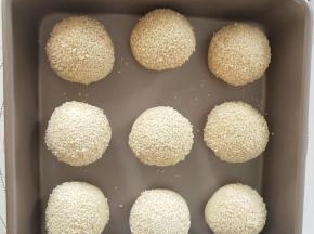 面包表面喷水，沾满白芝麻，放入学厨24*24厘米的烤盘中发酵到2倍大。
