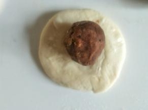 把面团略略按扁包入豆沙馅