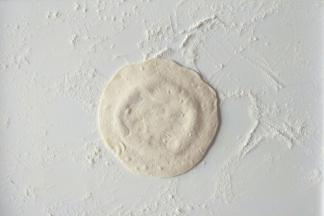 取一个小面团揉圆按扁擀成中间厚周边薄的面皮