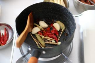 所有的菜都处理好后，重新在锅内倒入少许花生油，将花椒、大料、姜、蒜瓣、剁椒碎、泡山椒、香菜根煸香。