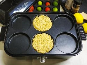 2.这里要用到Secite新思特多功能料理锅6圆盘，火力转到2档，将拌均匀的泡面放入圆盘里煎制