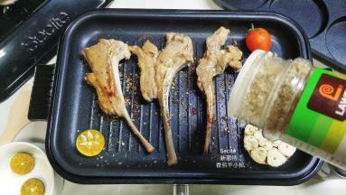 6.多功能锅转到2档，在羊小排上洒入杂锦香草
