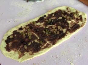 发好的面团排气后擀成长条状抹上豆沙，撒上蜜豆盖上保鲜膜松弛10分钟。