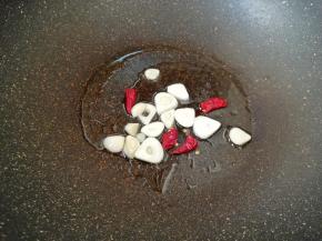 锅内重新倒油烧热，下入蒜片和干红辣椒炒香。