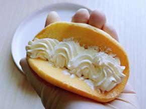 取一片蛋糕，挤上奶油，放两半草莓。