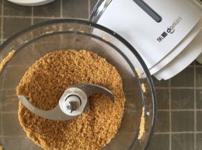 黄油隔热水融化成液体。消化饼干绞成饼干碎。