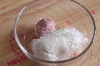 5、面团都需要用保鲜膜包裹住，防止风干。取一小块和红曲粉和匀，用于制作猪的嘴巴和耳朵，取非常小的一块和竹炭粉和匀，做眼睛。