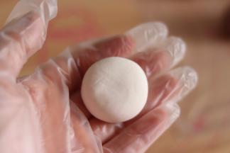 7、白色面团分成18克一个，搓圆，放到手中稍微压扁。