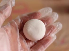 7、白色面团分成18克一个，搓圆，放到手中稍微压扁。