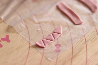 12、取一部分红色的面团，擀薄片后做出小三角形，再搓一个椭圆形。