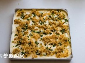 拌匀的面糊倒入已铺好油布的烤盘中，表面大致刮平，先撒上烘烤后的小葱，再撒上一层肉松。烘烤后的小葱水分减少，颜色相应的变得暗淡，但是不会影响蛋糕的起发。