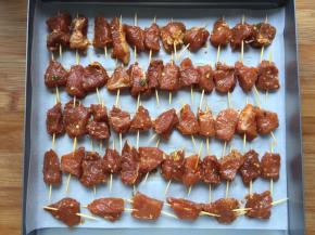 将肉一个一个串上放入烤盘，