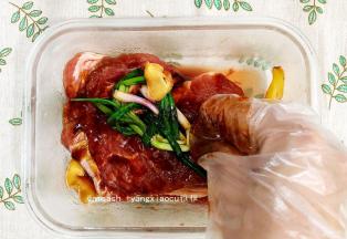 用手抓拌，让肉均匀地沾到酱汁，把姜片和葱结一起放入保鲜盒中，搓一搓，以使入味