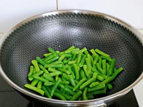 将焯水的刀豆倒入锅中翻炒。