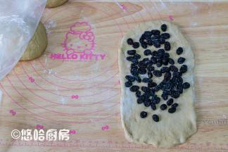 醒发后的面团压扁，上下擀开、翻面、再擀开，底边压薄，铺一层浸泡后的黑加仑，黑加仑用厨房纸蘸干水分再用。